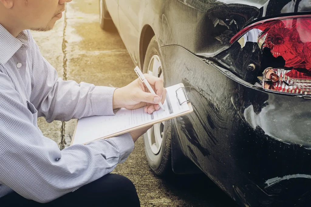 An insurance adjuster looking over a car.