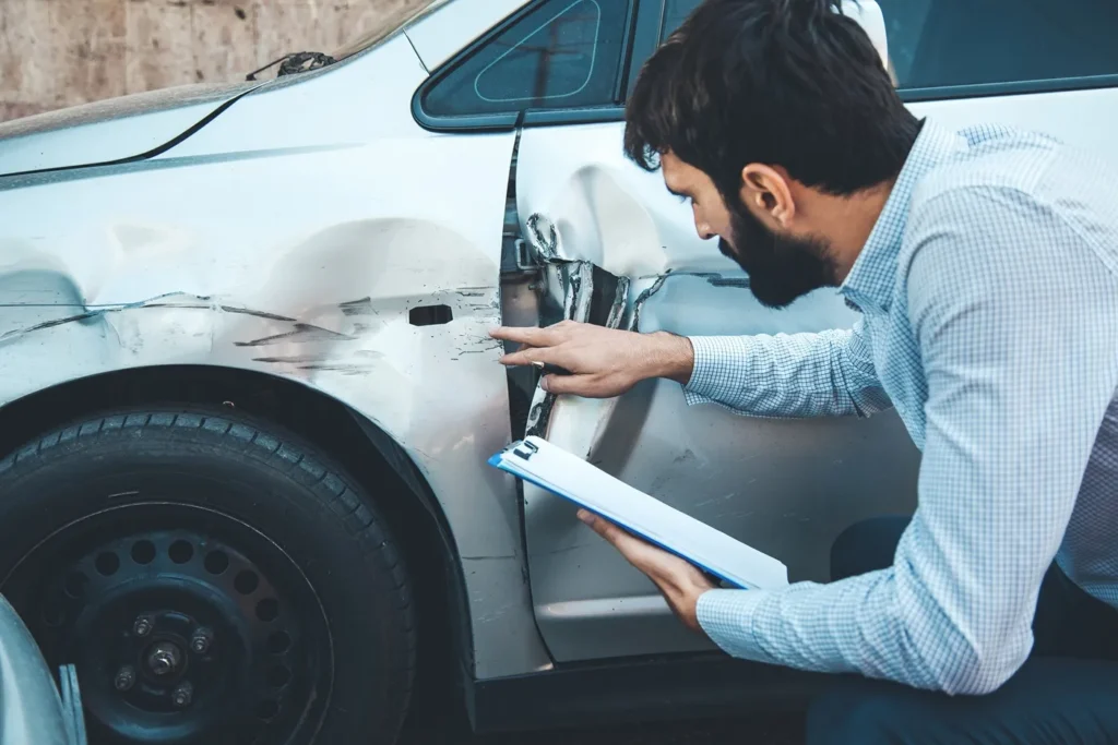 Insurance adjuster looking over a car.