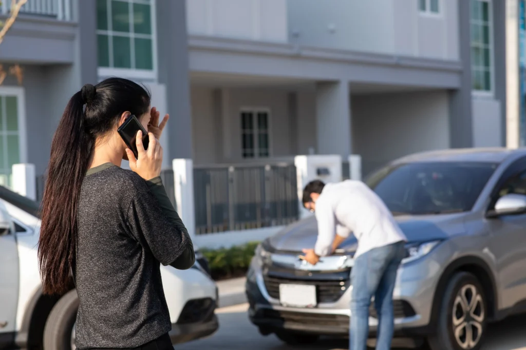 A woman and a man on their phones after an accident.