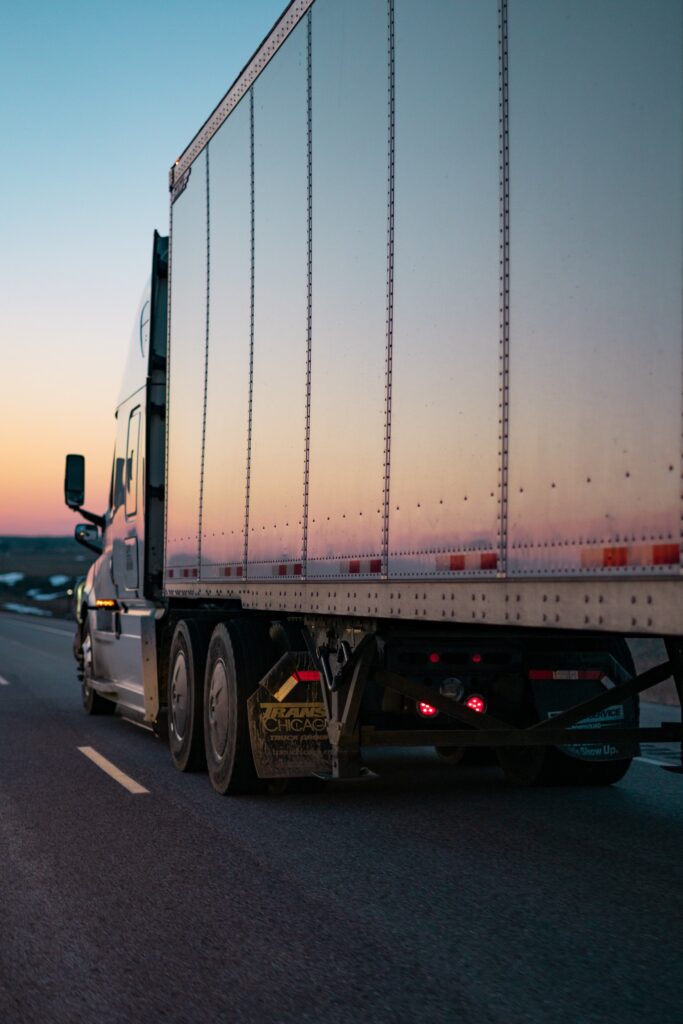 Semi-truck driving in sunset.
