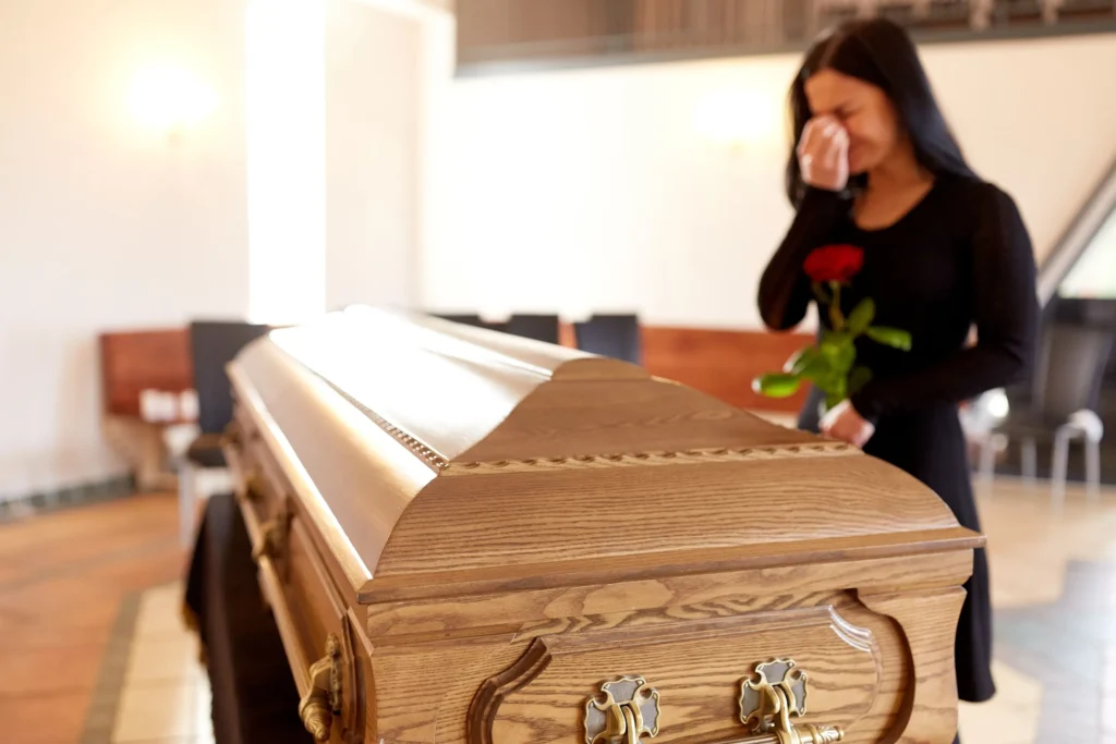 A woman crying at a casket.