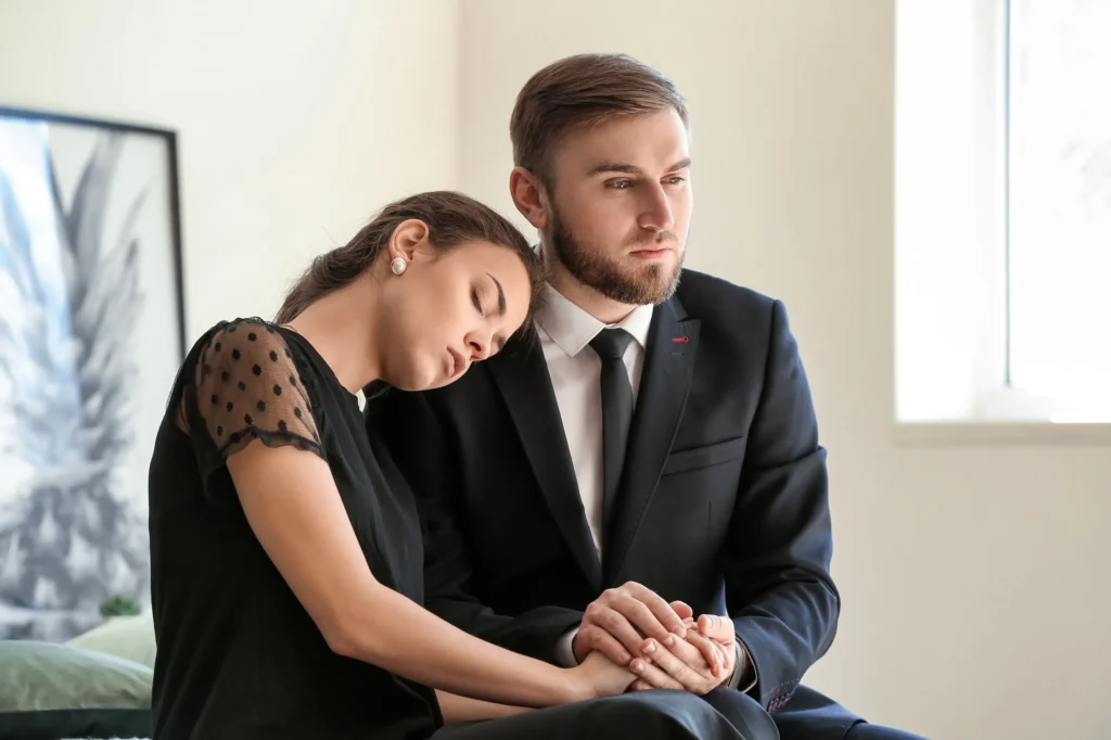 Two people mourning at a funeral.