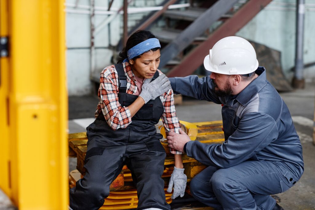 An injured industrial worker being checked by a manager.